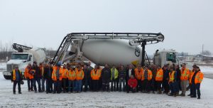 A group of people posing in front of a concrete mixer.