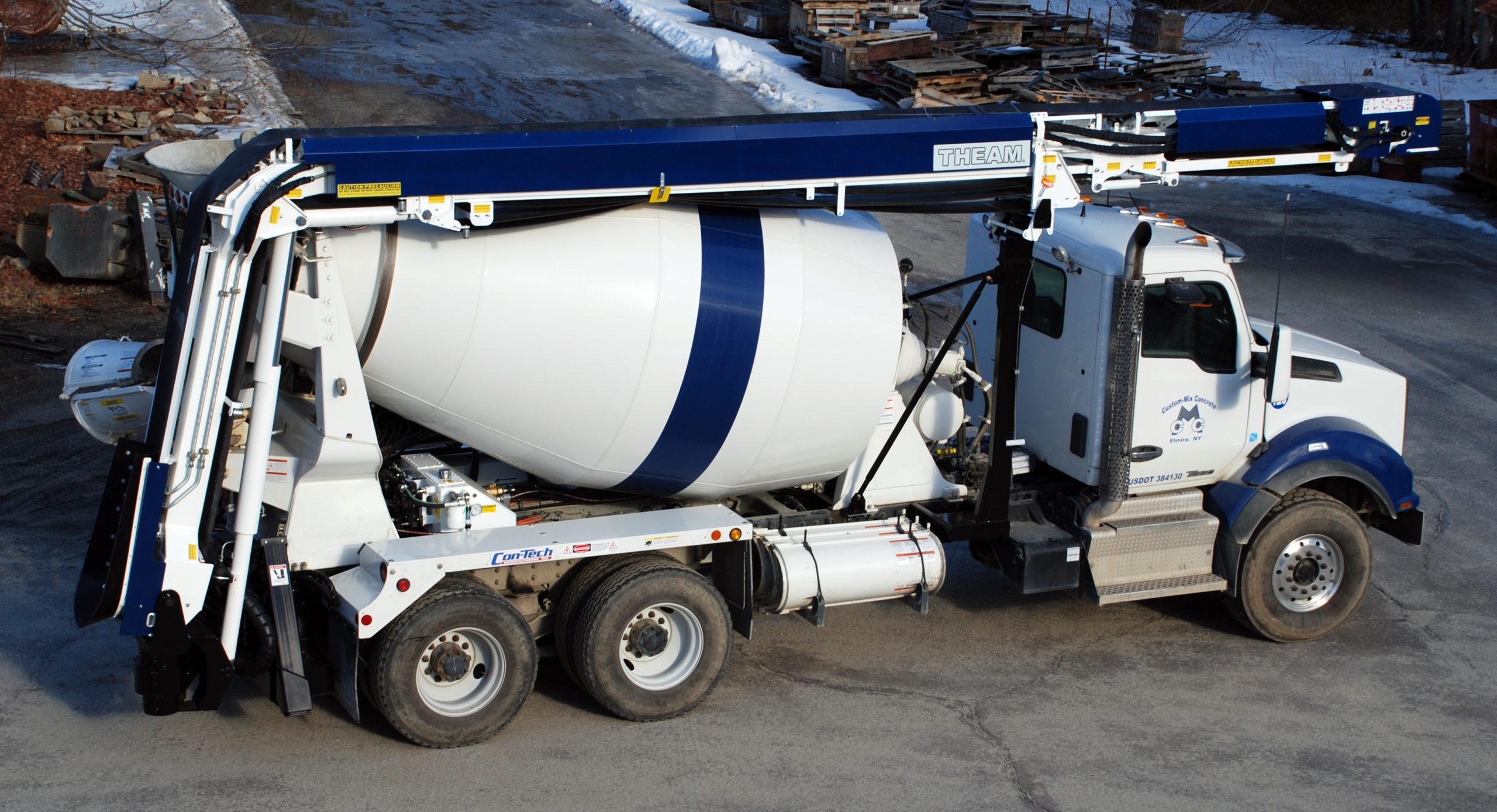 A concrete mixer truck is parked in a snowy area.