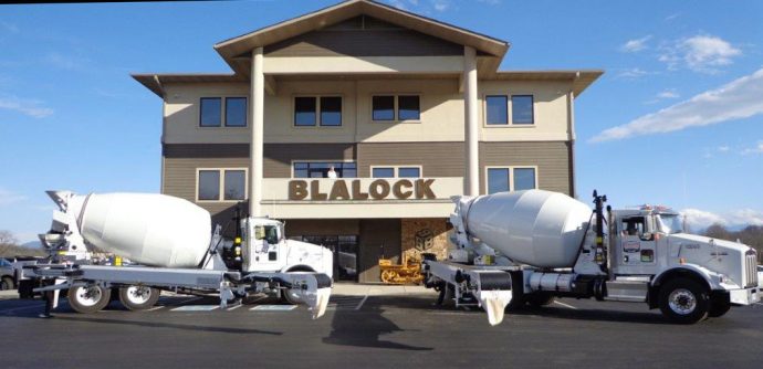 Two cement trucks parked in front of a building.