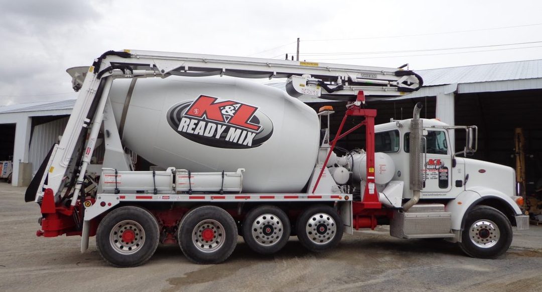 A cement mixer truck is parked in front of a building.
