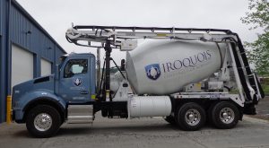 A cement truck is parked in front of a building.