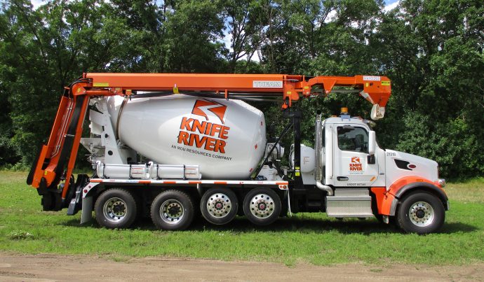 A concrete mixer truck is parked in a field.