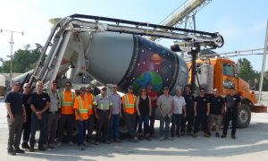 A group of people standing in front of a concrete mixer.