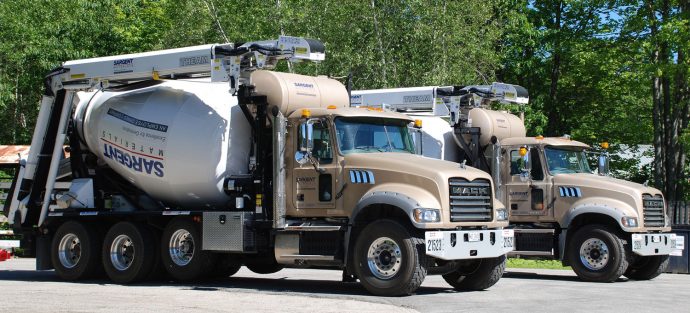 Two cement mixer trucks parked in a parking lot.