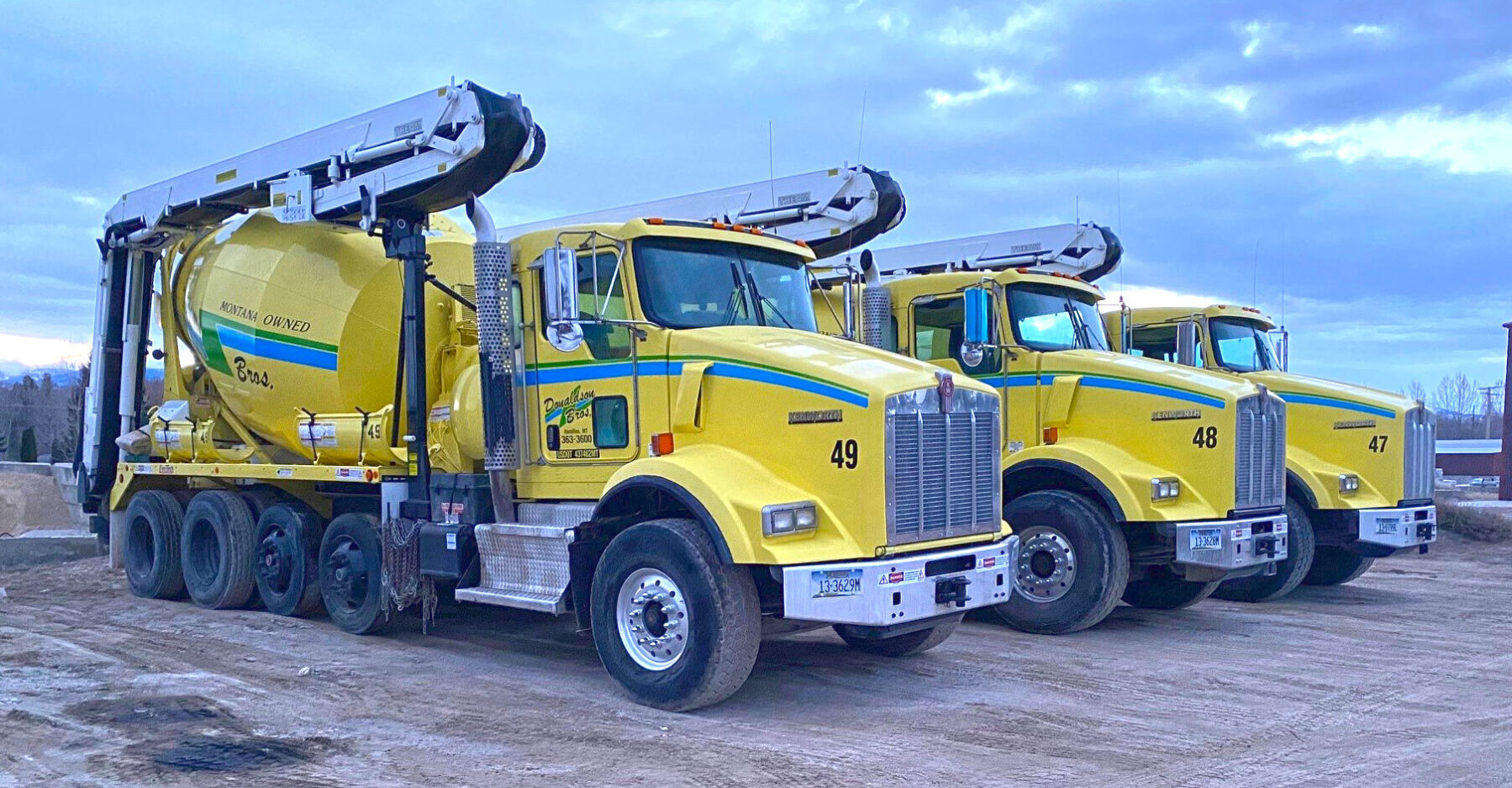 Three yellow cement trucks parked next to each other.