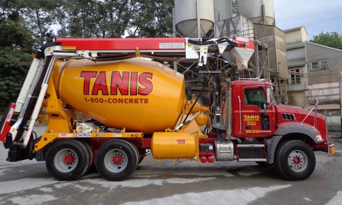 A concrete mixer truck is parked in front of a building.