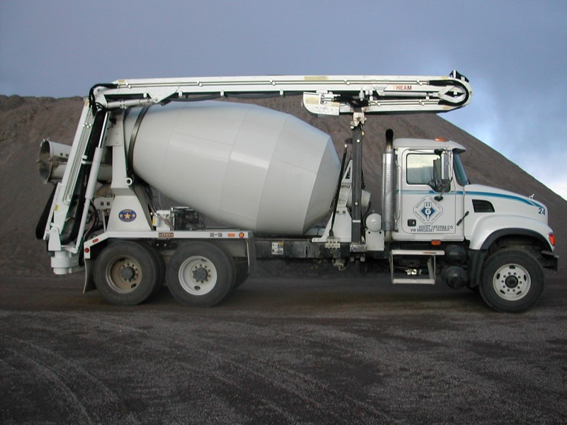 A cement mixer truck parked on a dirt road.