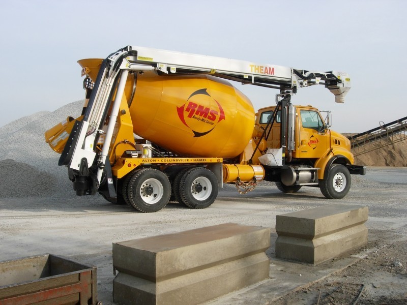 A cement mixer is parked in front of a concrete block.