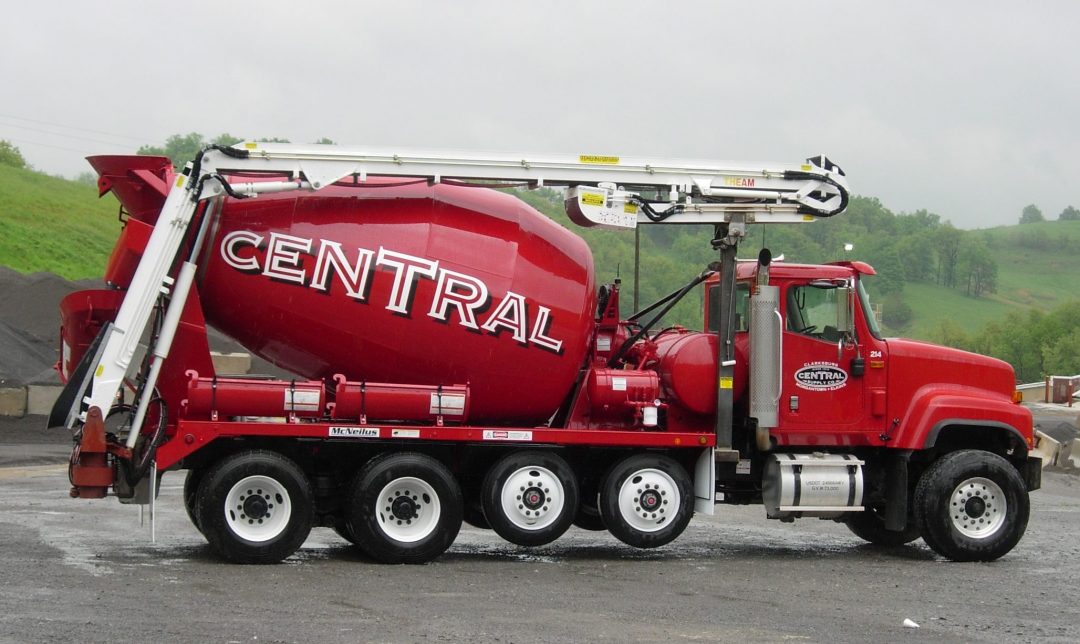 A red cement mixer is parked in a parking lot.