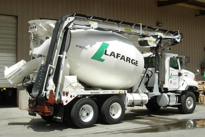 A white cement mixer truck is parked in front of a building.