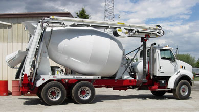 A white cement mixer truck parked in front of a building.