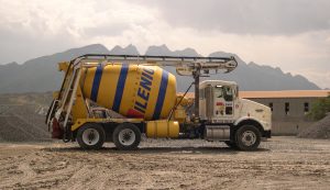 A cement mixer is parked in front of a mountain.