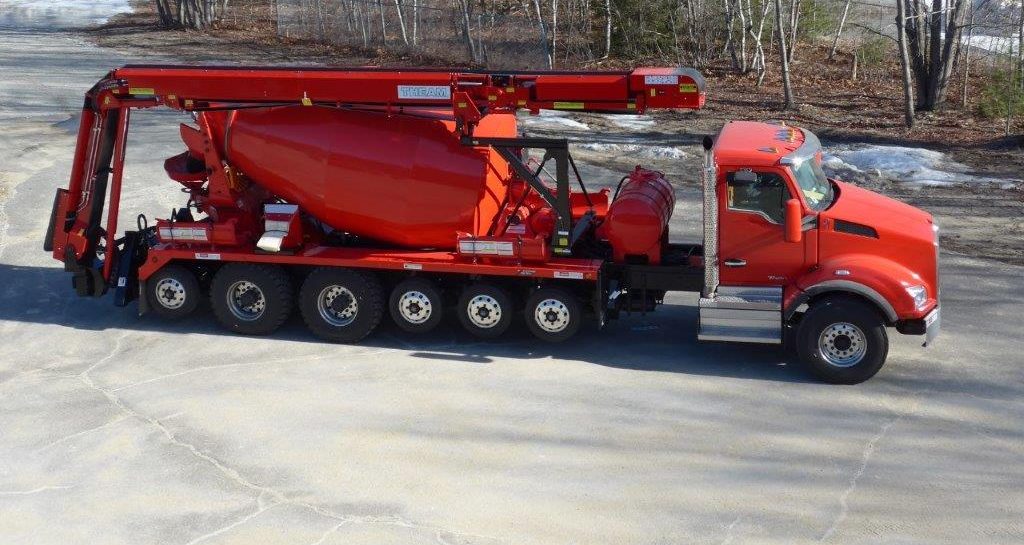 A red concrete mixer truck is parked in a parking lot.