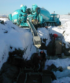 Mixer trucks feeding a THEAM conveyor on a snowy job site