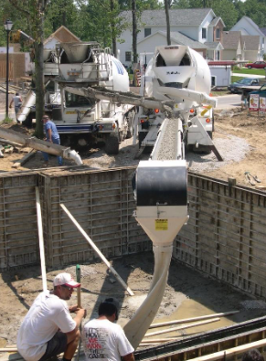 Crew placing concrete into foundation forms from a THEAM conveyor