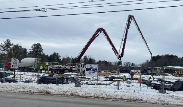 Concrete pump boom stretched across a job site to reach an easy point of pour
